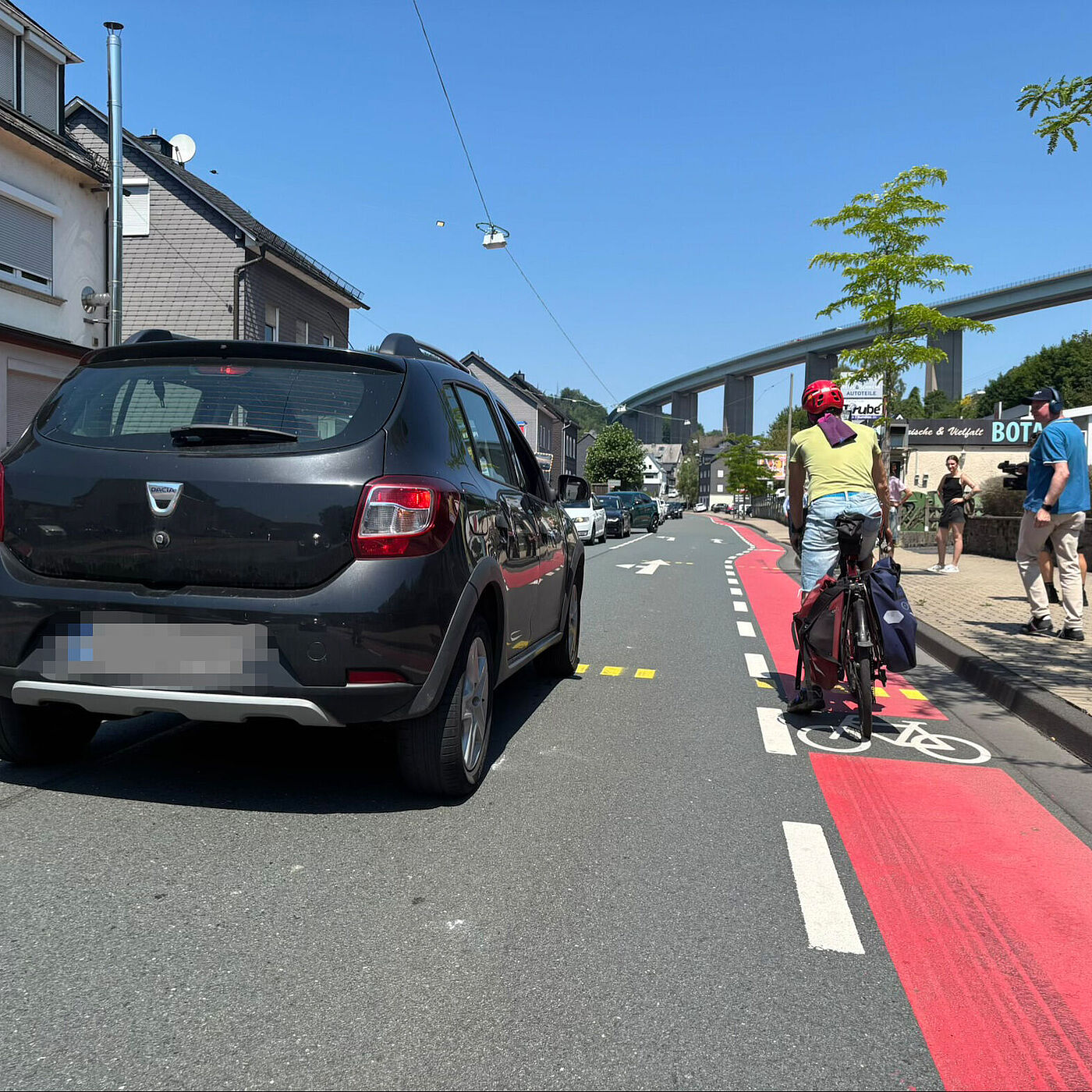 Eine Person im Auto überholt einen Radfahrer in Siegen-Eiserfeld auf der Eiserfelder Straße.