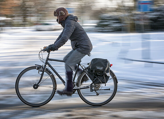 Ein Radfahrer auf einer winterlichen Straße mit Schnee.